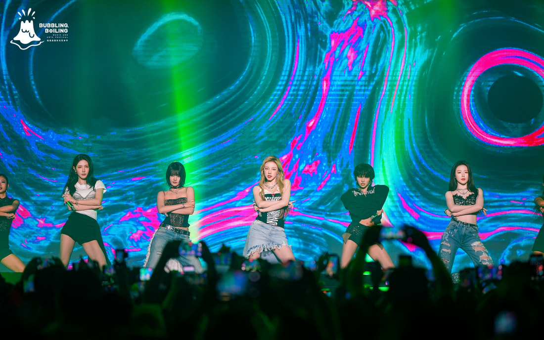 A group of dancers performing on stage with a colorful abstract background, showcasing a dynamic choreography.