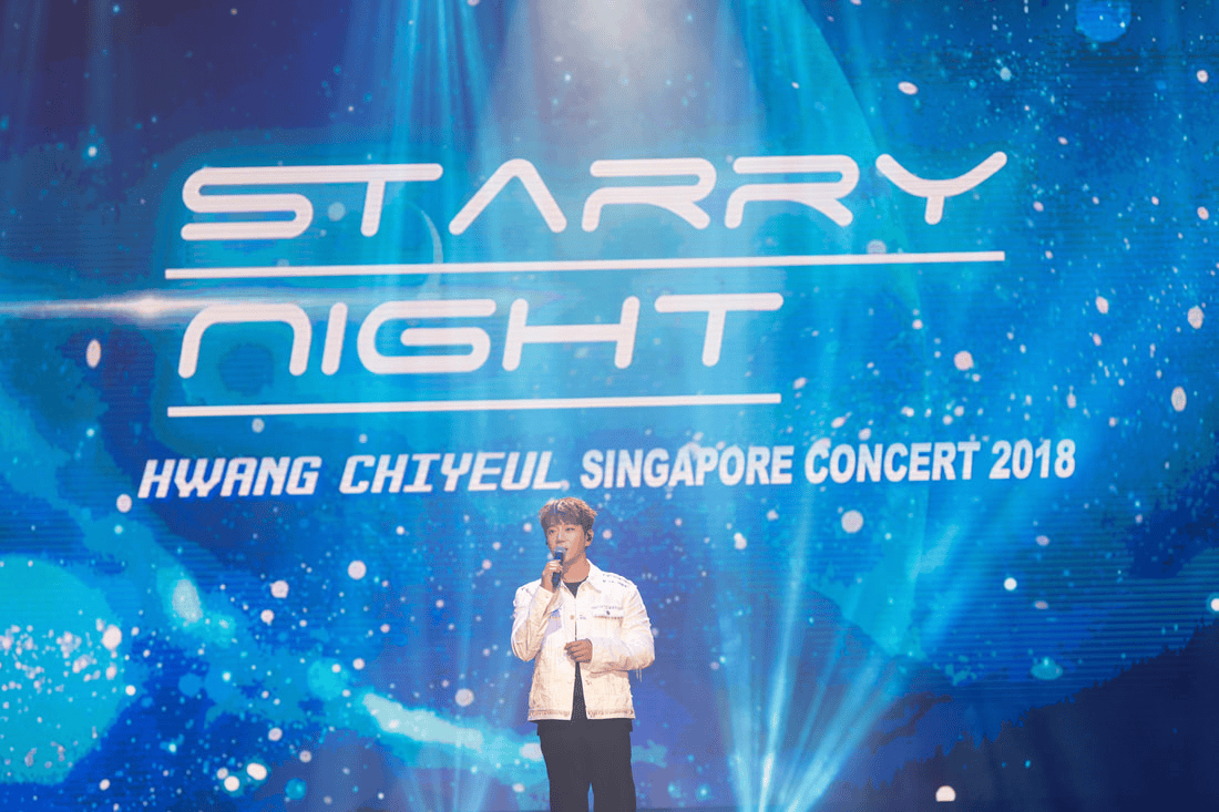 Hwang Chi Yeul performing at the 'Starry Night' concert, Singapore 2018, with a blue and starry backdrop.