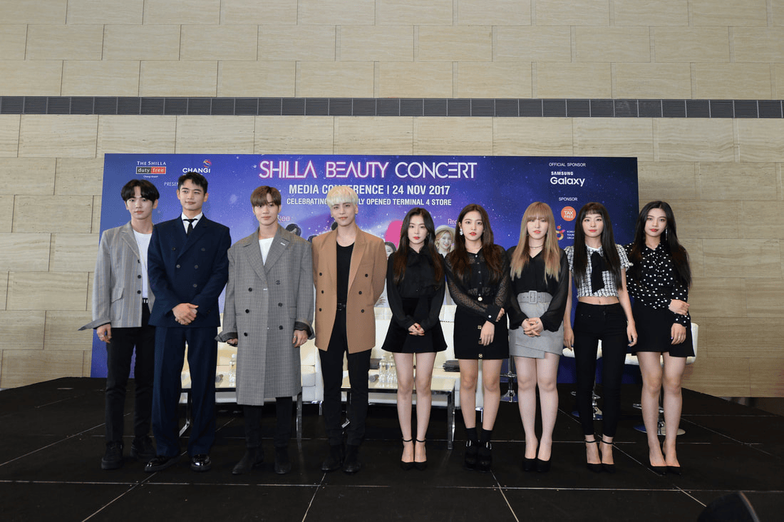 A group of eight individuals posing for a photo at the Shilla Beauty Concert media conference on November 24, 2017. They are dressed in stylish outfits and standing in front of a promotional backdrop.